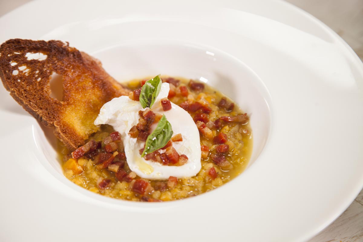 Poached eggs with red-yellow hulled Lentils and crisp bacon